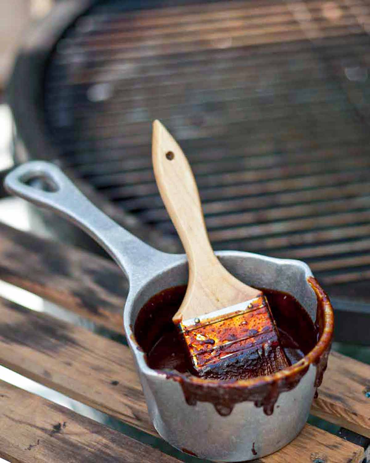 A small pot filled with North Carolina barbecue sauce with a brush resting inside.