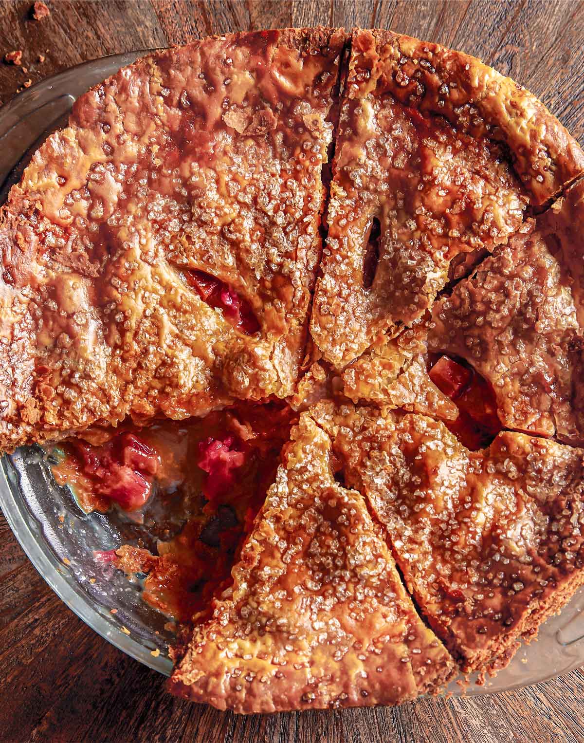 A rhubarb brown sugar pie cut into 7 wedges with one slice missing.