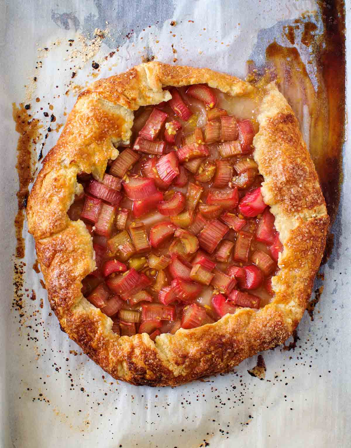 Eine ganze gebackene Rhabarber-Ingwer-Crostata auf einem Stück Pergamentpapier.