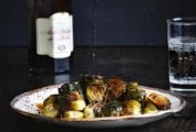 A plate of roasted Brussels sprouts with a drizzle of balsamic vinegar splashing down on it.