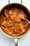 Thin slices of pork in a pot that are being cooked for bifanas.