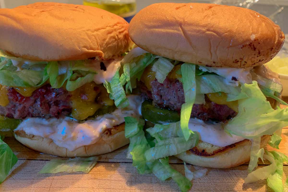 Two pastrami burgers with Russian dressing and iceberg lettuce.
