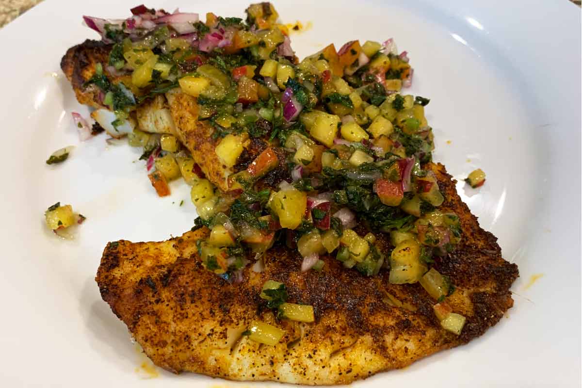 A piece of blackened grouper with peach jalapeño salsa on top.