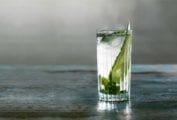 A highball glass filled with British summertime cooler, mint leaves, and a cucumber slice.
