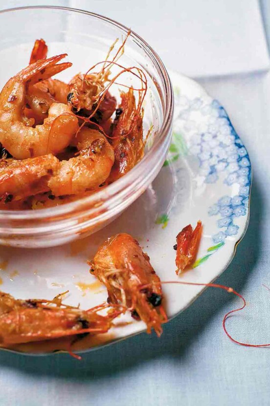 Glass bowl filled with garlic shrimp, sautéed with oil, butter, chiles pepper, and garlic.