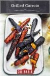 A white enamel platter topped with charred purple and orange grilled carrots.