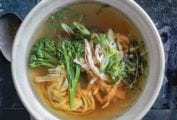 A bowl of healthy egg drop soup with shredded chicken, green onions, broccoli rabe, noodles, and sprouts