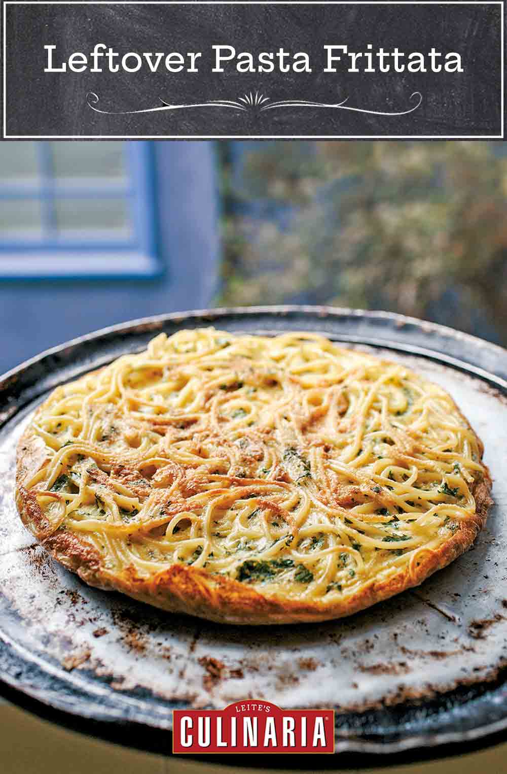 A cooked leftover pasta frittata on a round metal pan.