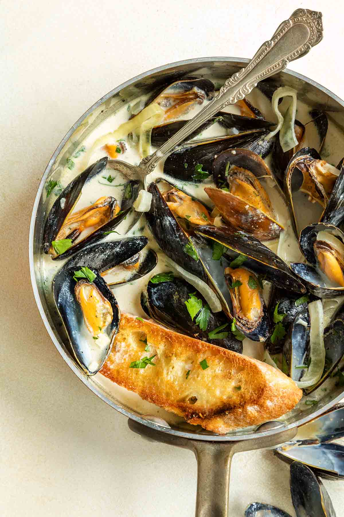 A copper saucepan filled with mussels in a creamy white wine garlic sauce with lemons.
