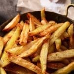 A metal bowl with handles filled with seasoned perfect French fries.