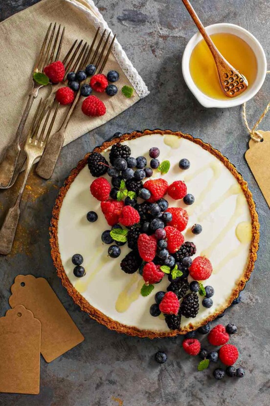 A red, white, and blue tart with a graham cracker crust, cream cheese filling, and raspberries, blueberries, and blackberry on top