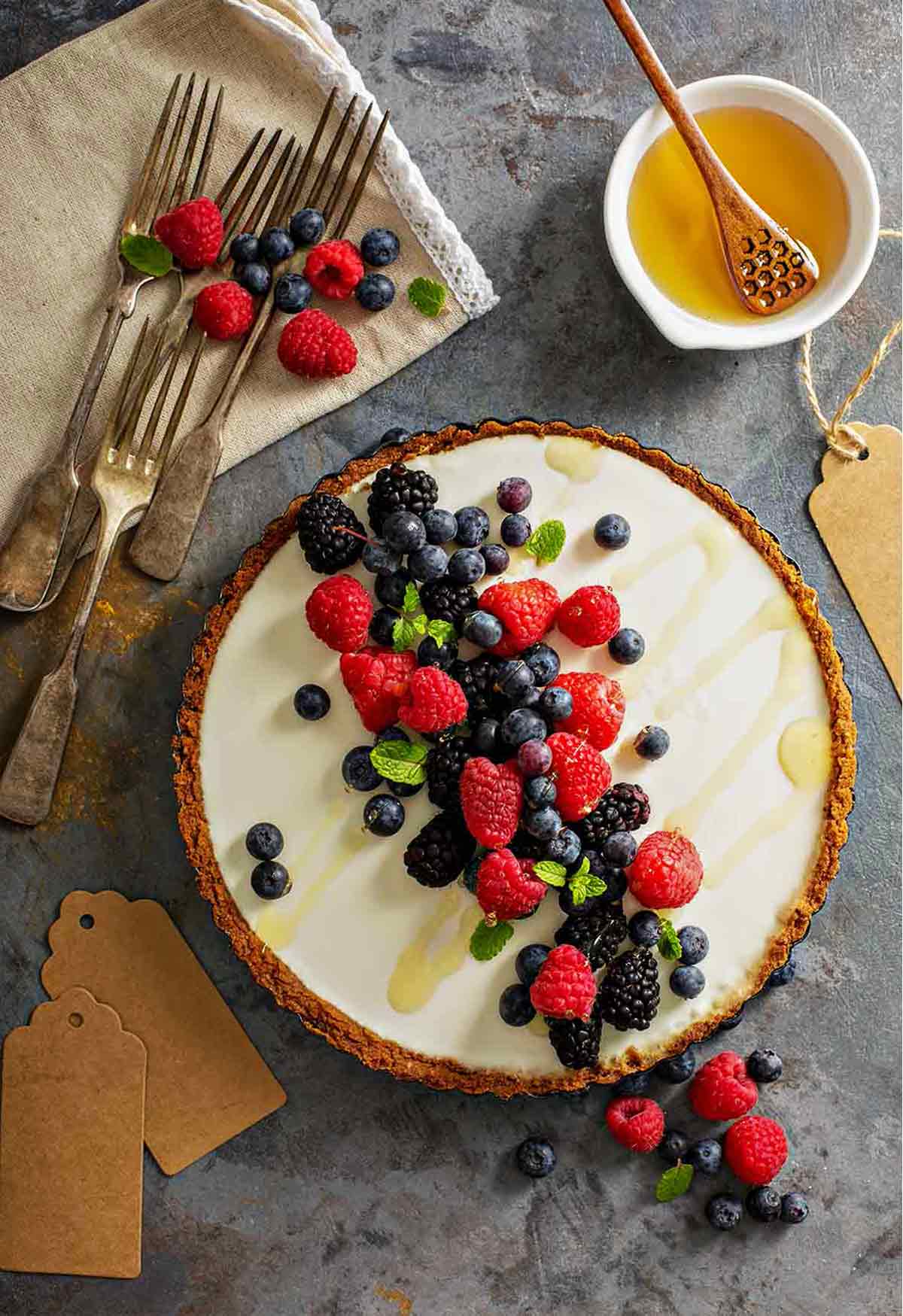 A red, white, and blue tart with a graham cracker crust, cream cheese filling, and raspberries, blueberries, and blackberry on top