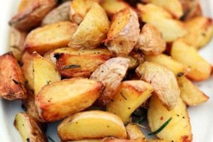 A platter of quartered roasted potatoes on the grill, seasoned with pepper and rosemary.