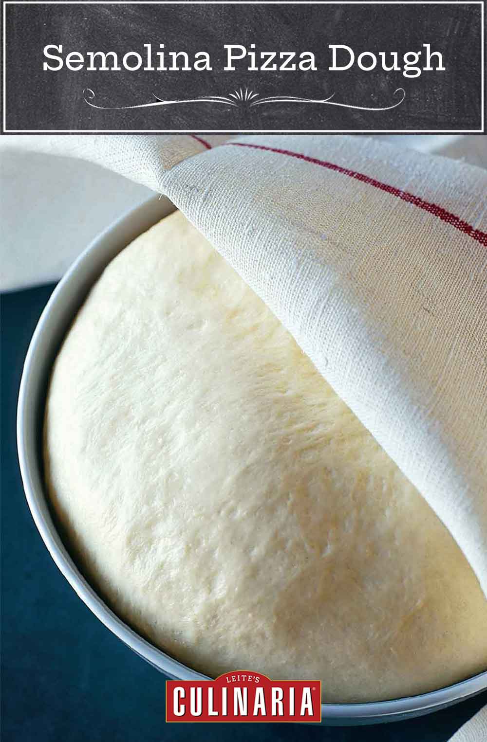 A ball of rising semolina pizza dough in a round metal tin, partially covered by a kitchen towel.