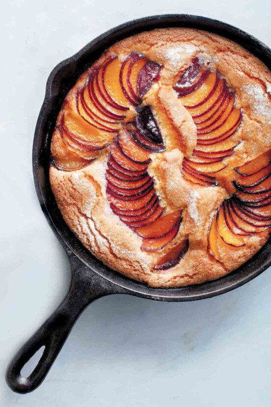 A cast-iron skillet plum cake with slices of fanned out plums baked in