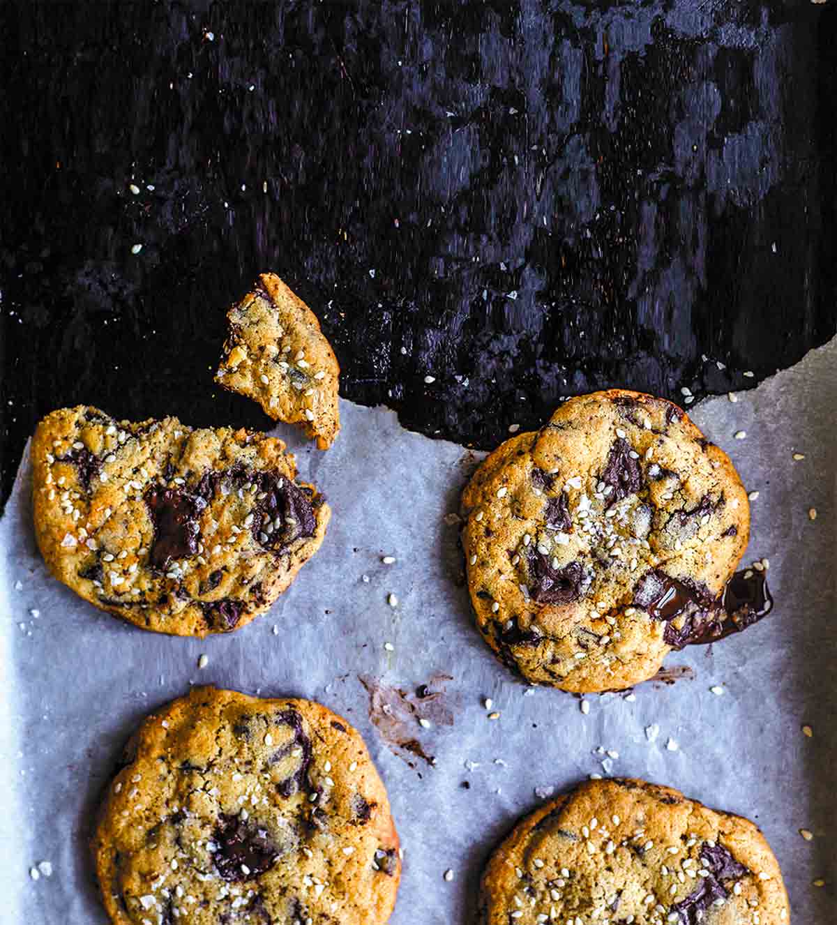 A few tahini chocolate chip cookies on a torn piece of parchment paper.