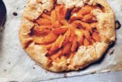 A cooked apricot galette on a piece of parchment paper with a metal spatula beside it.