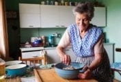 An elderly woman mixing bater in a enameled bowl to illustrate how cooking reminds you who you are.