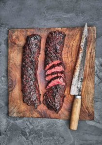 Two pieces of Korean style steak on a cutting board with a knife.