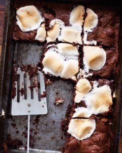 A tray of s'mores brownies with a spatula resting inside and several brownies missing.
