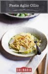 A bowl of spaghetti all'Aglio e Olio topped with olive oil and flakes of Parmesan cheese.