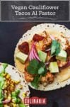 Two soft corn tacos filled with vegan cauliflower tacos al pastor--with pineapple chunks, pickled onions, cashew queso, avocado, cilantro