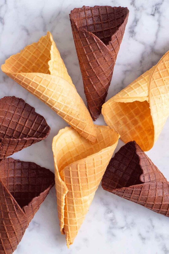Vanilla and chocolate waffle cones on a white marble surface.
