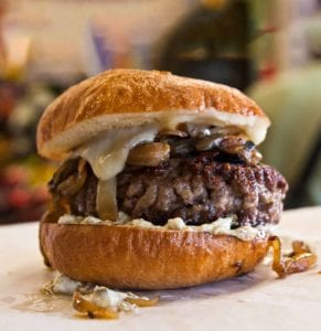Big fat juicy burger with caramelized onions, melted cheese, and a toasted hard roll