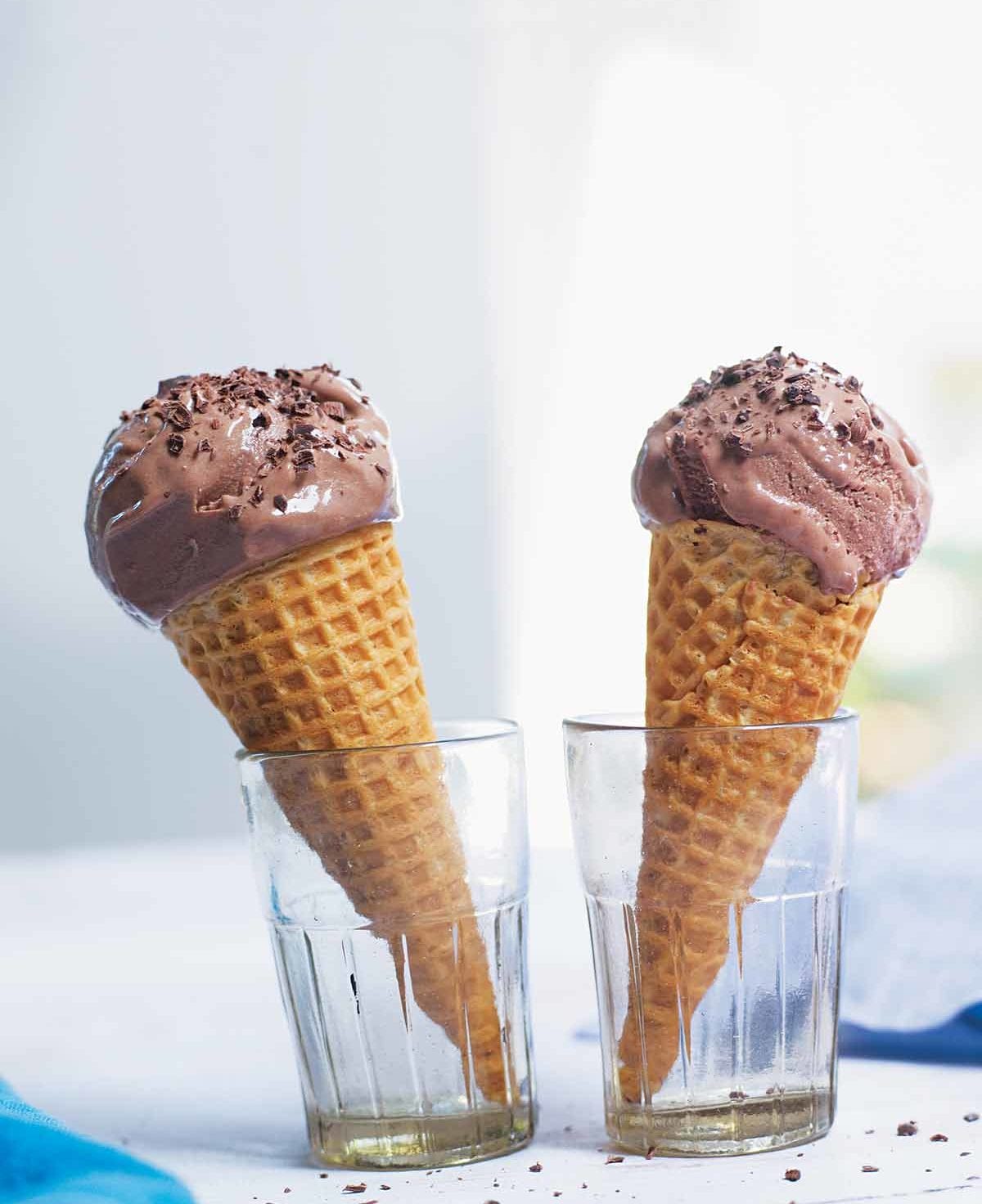 Two bitter chocolate and buttermilk ice cream cones in glasses.