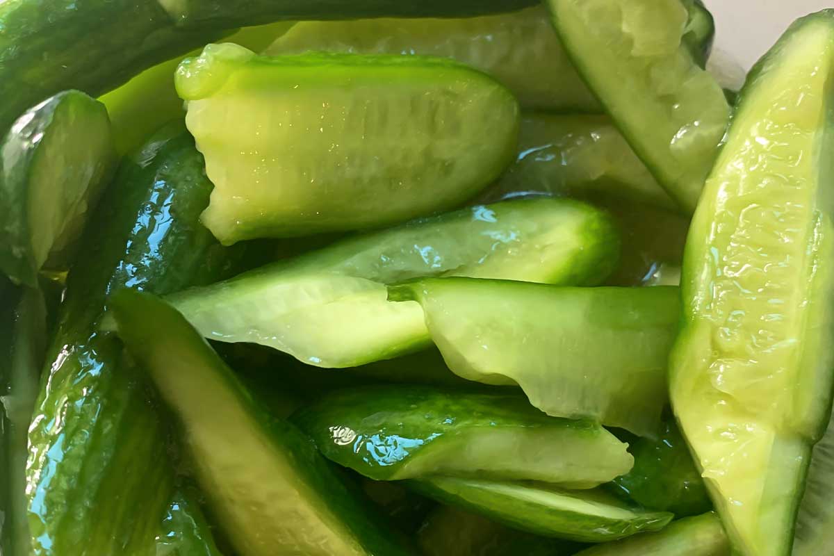 A close shot of smashed cucumbers being prepared for Chinese smashed cucumber salad.