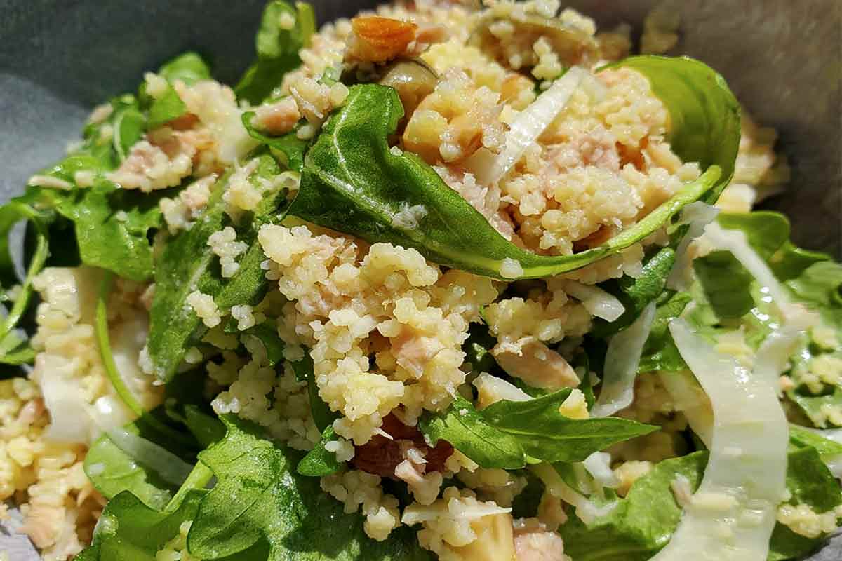 A close shot of couscous salad with fennel and almonds and arugula.