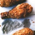 Crispy fried chicken pieces on grease-stained paper.