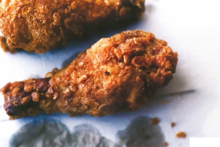 Crispy fried chicken pieces on grease-stained paper.
