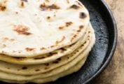 A stack of flour tortillas with bacon fat on a cast-iron skillet.