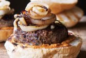 A lamb burger on half a bun topped with grilled Spanish onions.