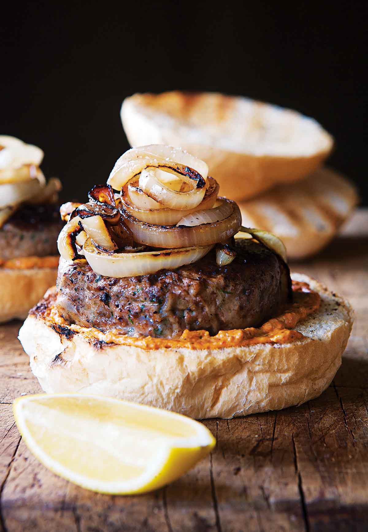 A lamb burger on half a bun topped with grilled Spanish onions.