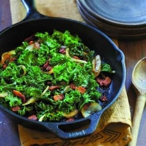 Lodge Pre-Seasoned Cast Iron Skillet With Assist Handle with greens in it.