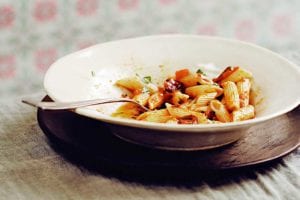 White bowl with ziti and a pasta puttanesca sauce