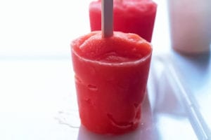 Two red tropical fruit popsicles on a plastic tray.