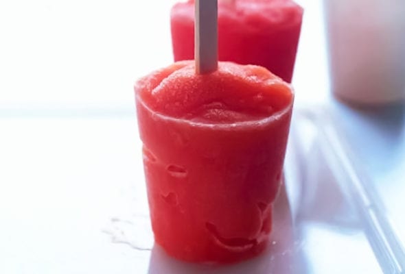 Two red tropical fruit popsicles on a plastic tray.