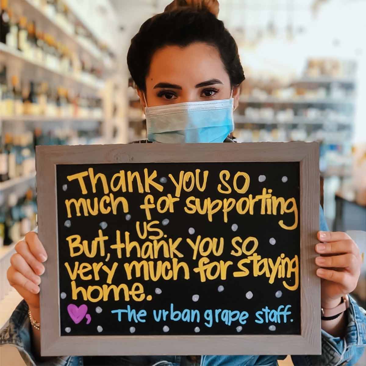 A woman holding a chalkboard sign thanking people for their support.