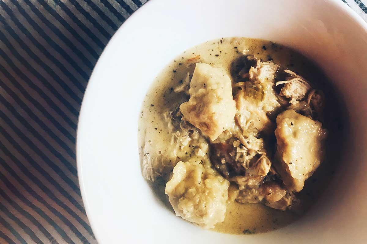A white bowl filled with chicken and dumplings.