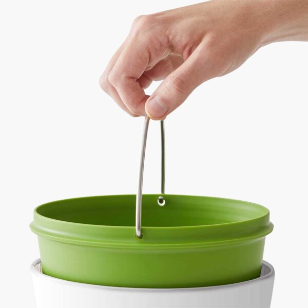 EcoCrock Counter Compost Bin with person holding handle.