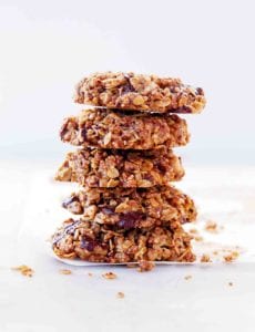 A stack of gluten-free vegan oatmeal cookies with chocolate on a white sheet.