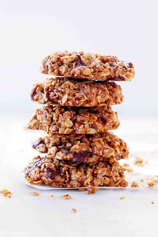 A stack of gluten-free vegan oatmeal cookies with chocolate on a white sheet.