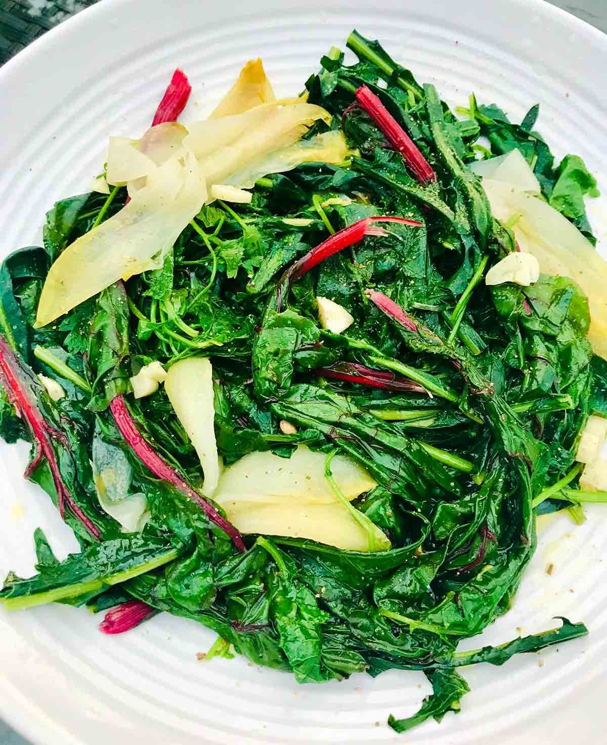 A white plate filled with horta, or boiled greens with garlic.