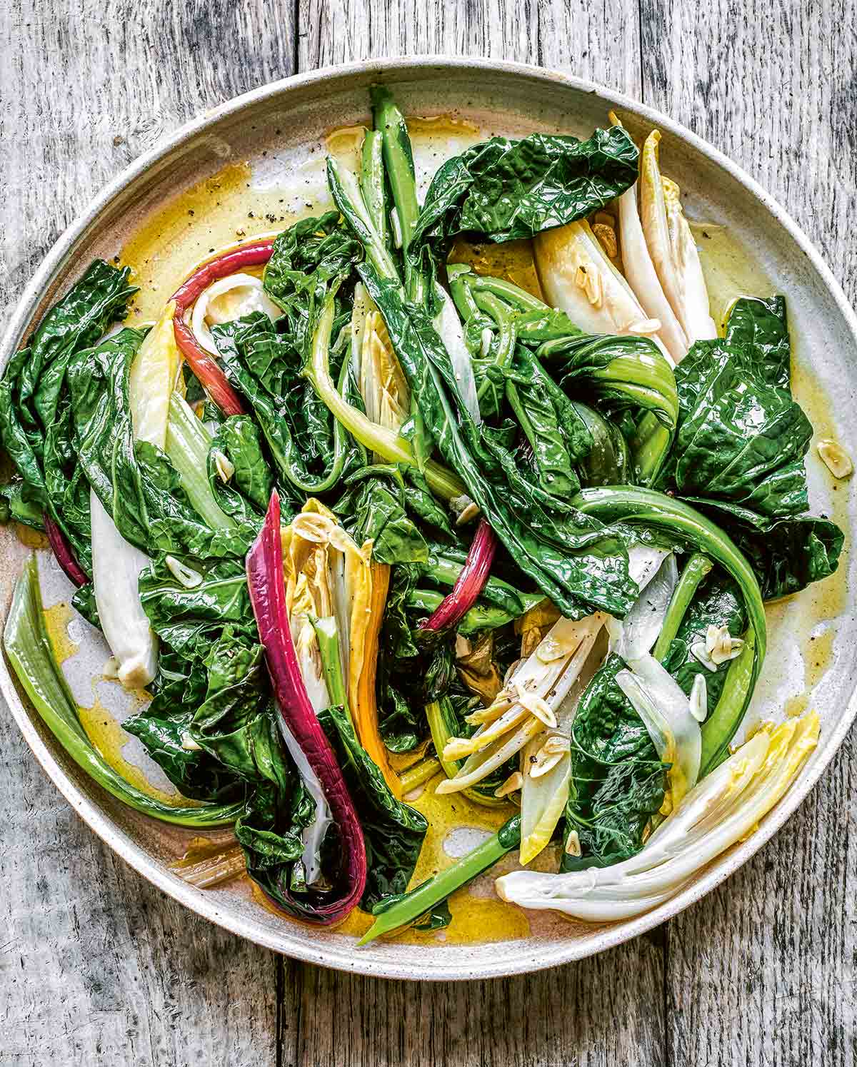 A white plate filled with horta, or boiled greens with garlic.