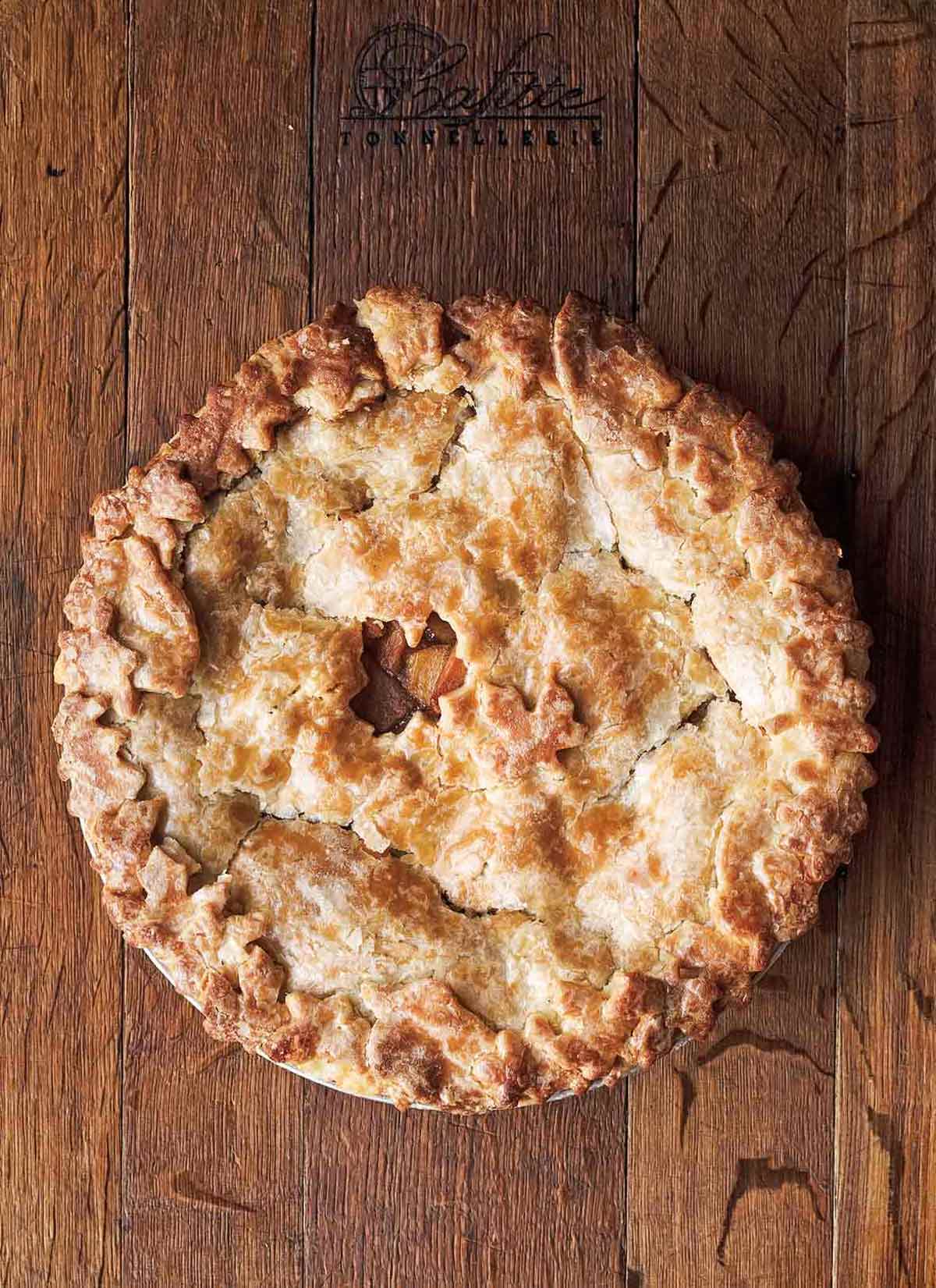 A baked hot buttered rum apple pie on a wooden board.