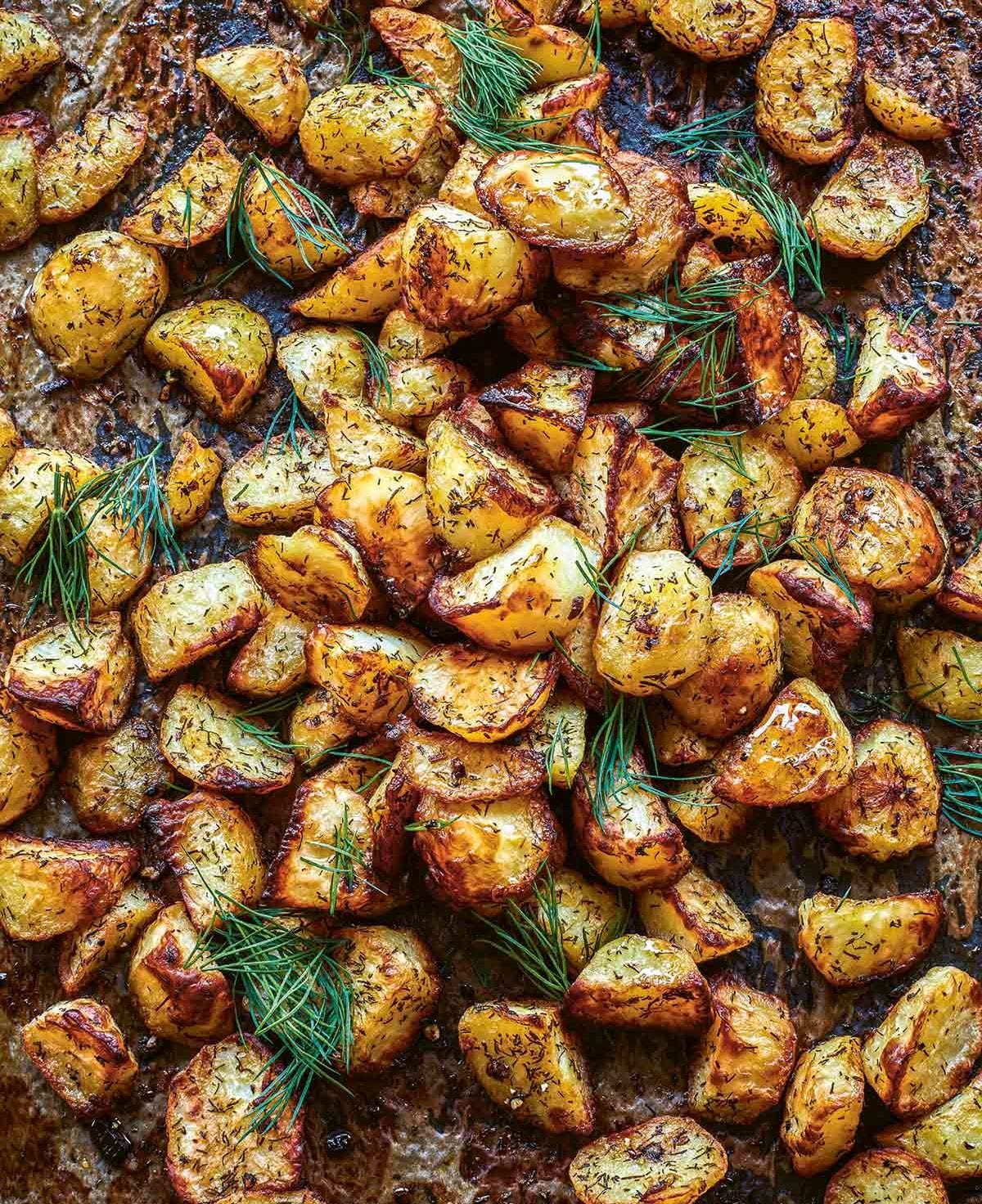 Roasted potatoes with dill on a baking sheet.