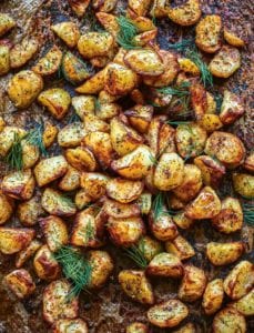 Roasted potatoes with dill on a baking sheet.
